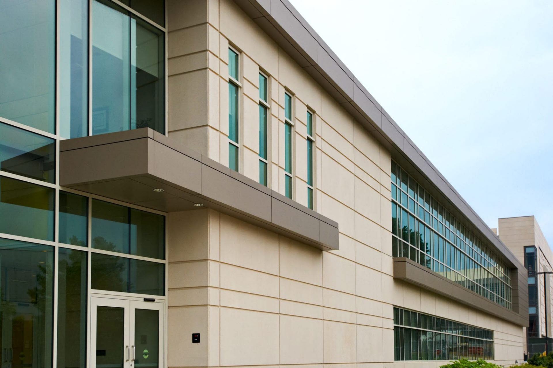 side of a precast building showing tan and brown walls with windows incorporated