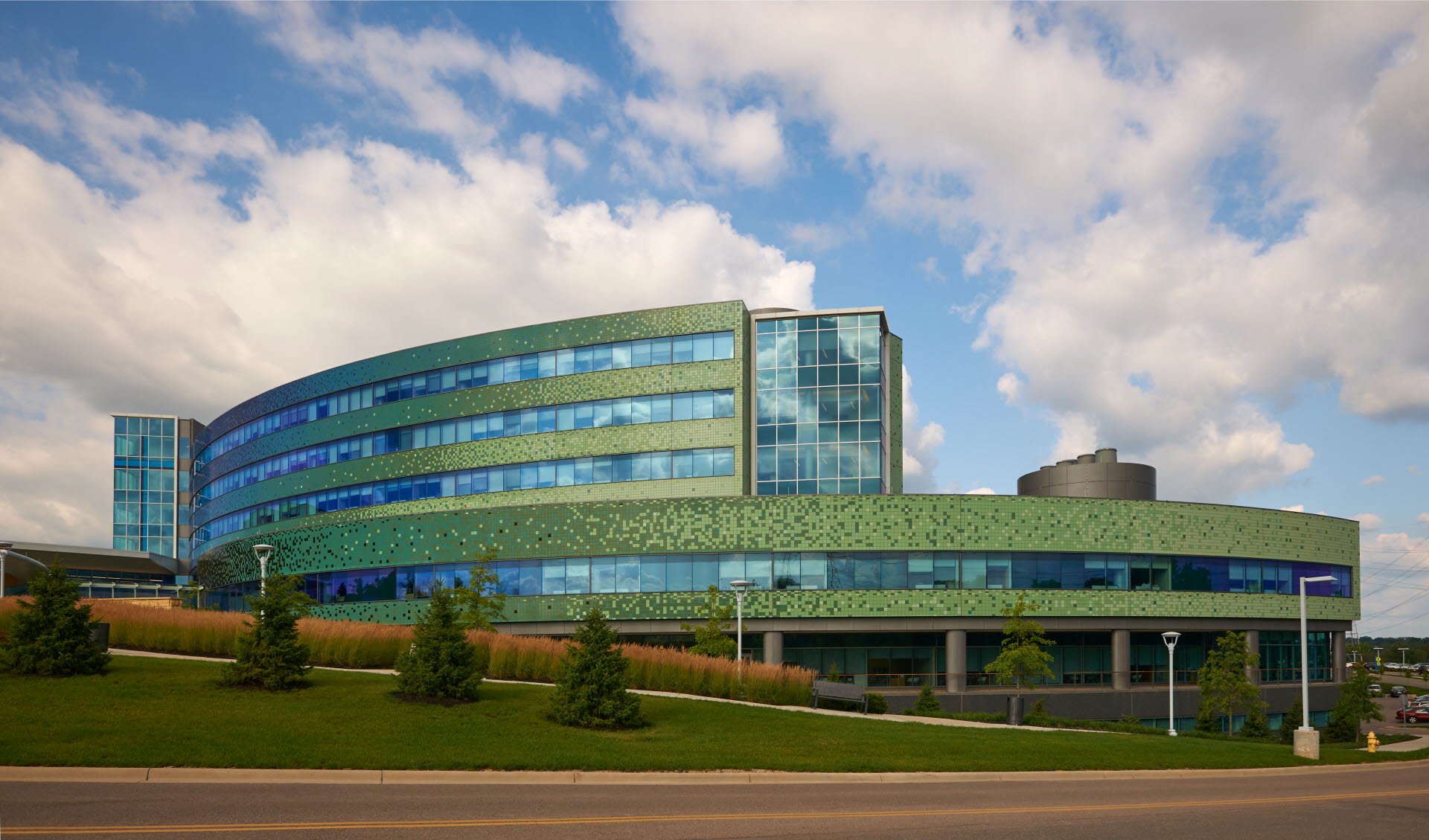 wide view of a precast concrete building made with green tiles and lots of windows.